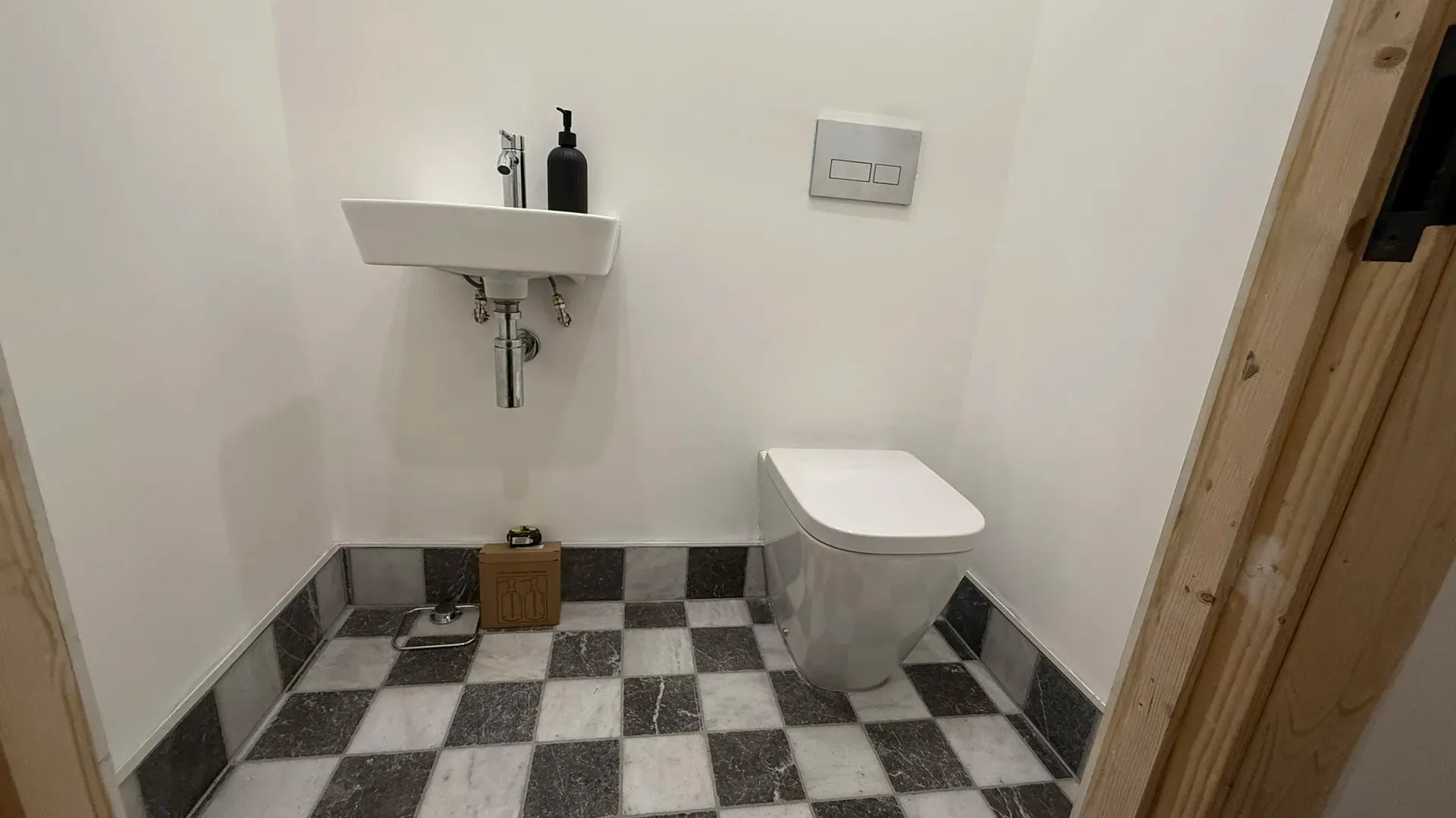 Wall-hung basin and concealed-cistern toilet above a chequerboard tiled floor