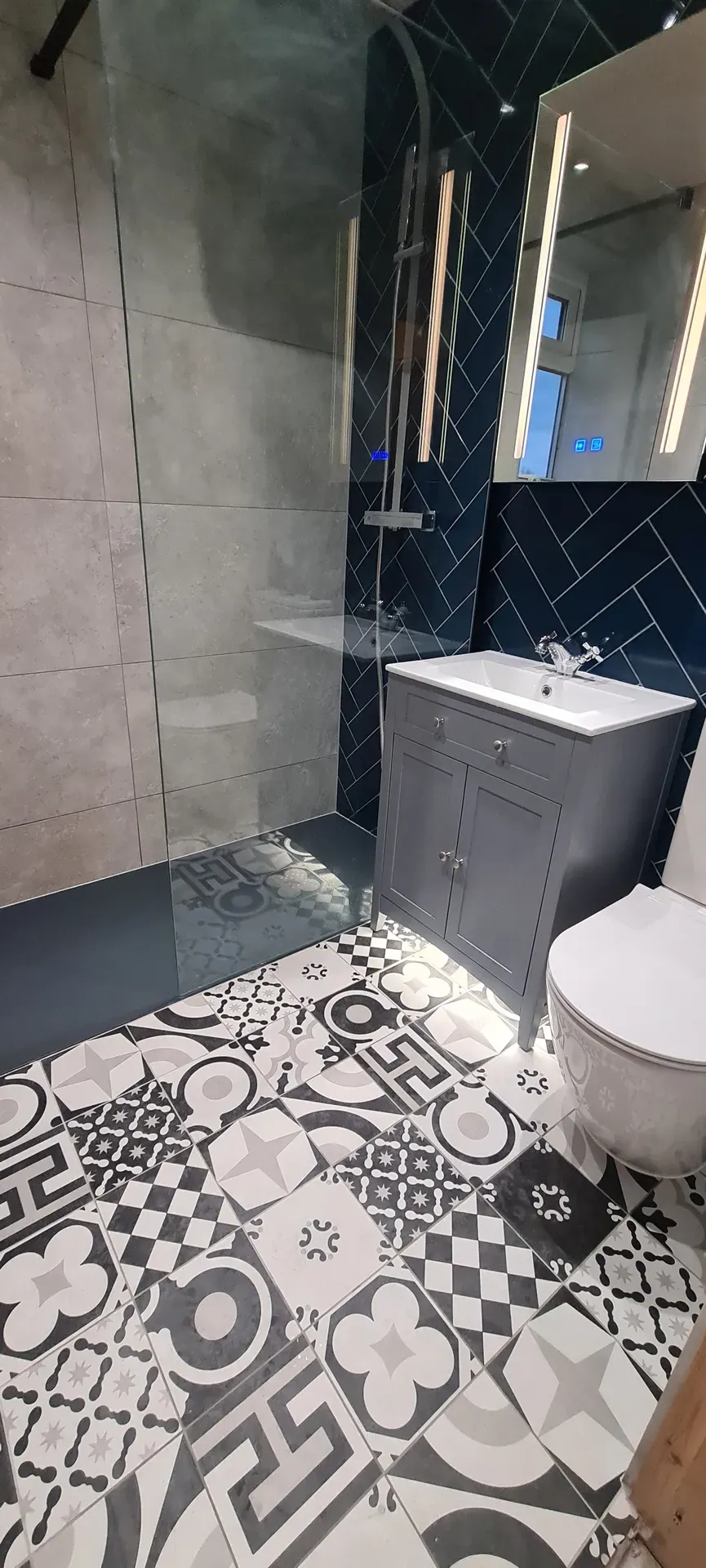Grey vanity unit and wall-hung toilet on a patterned encaustic-style floor