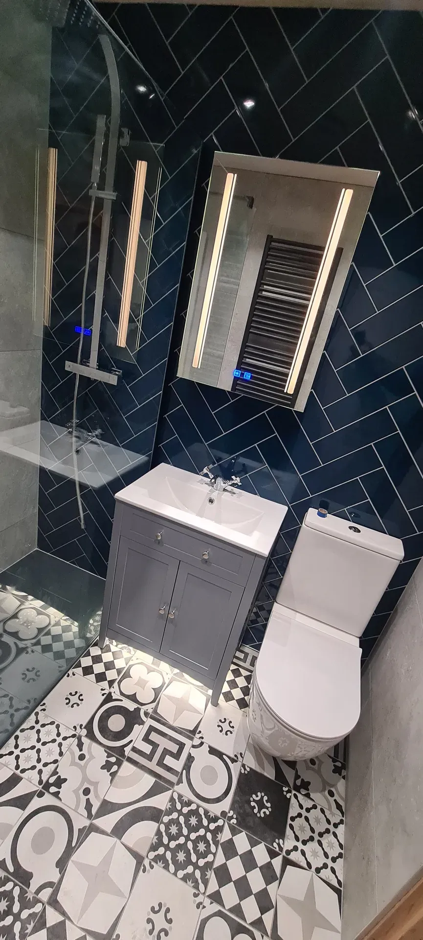 Navy herringbone tiled bathroom with a grey vanity unit and toilet