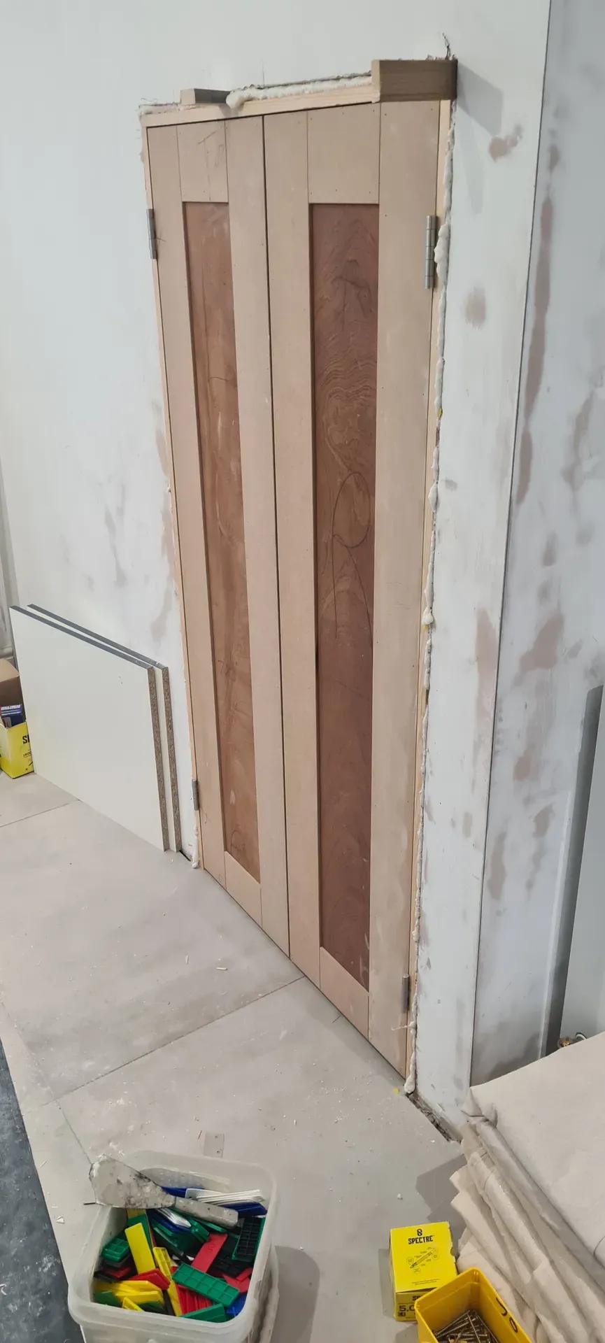 Stud framework and tiled wall part-way through a first-fix joinery installation