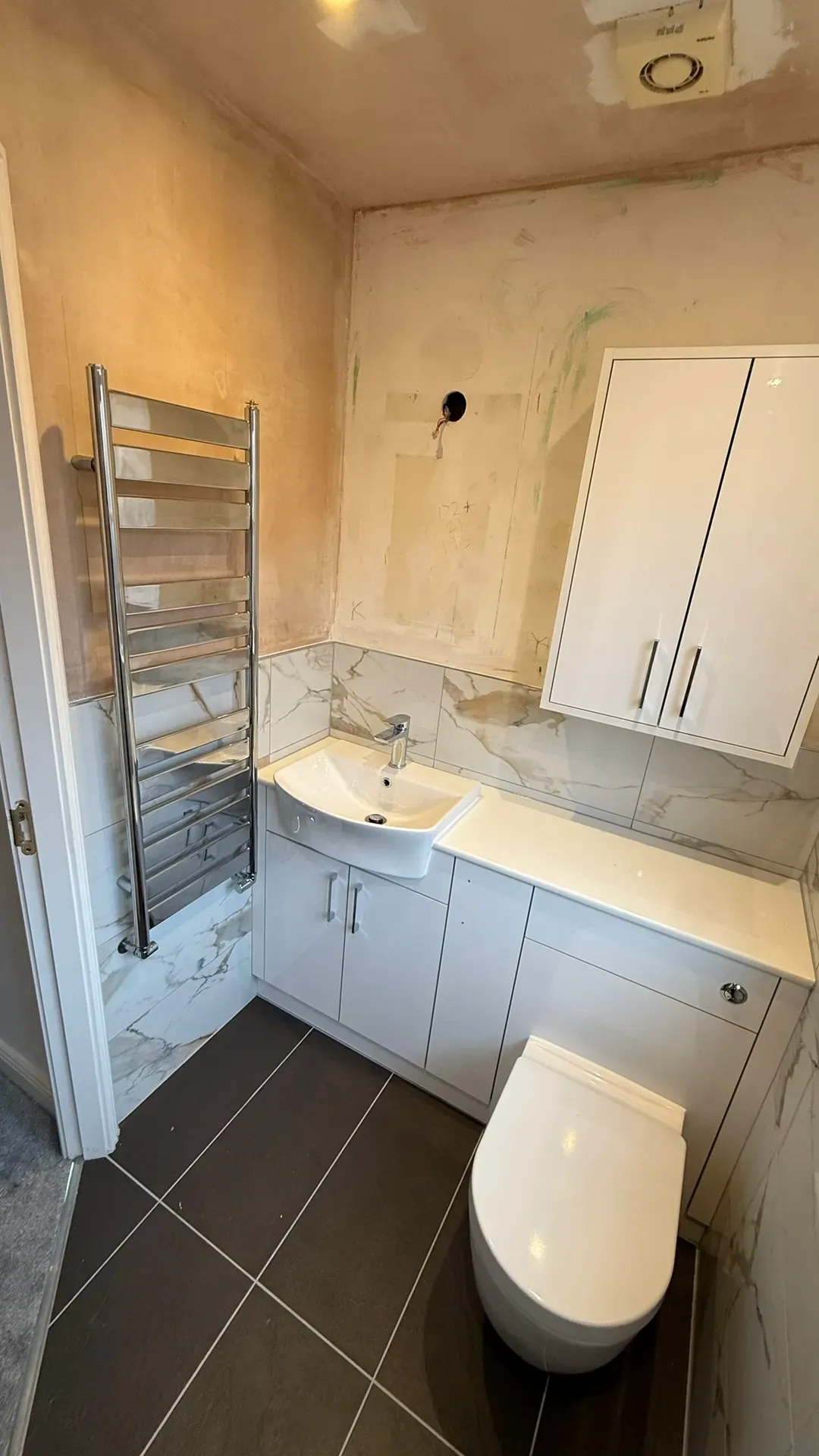 Fitted vanity units, wall cupboards and a chrome towel radiator
