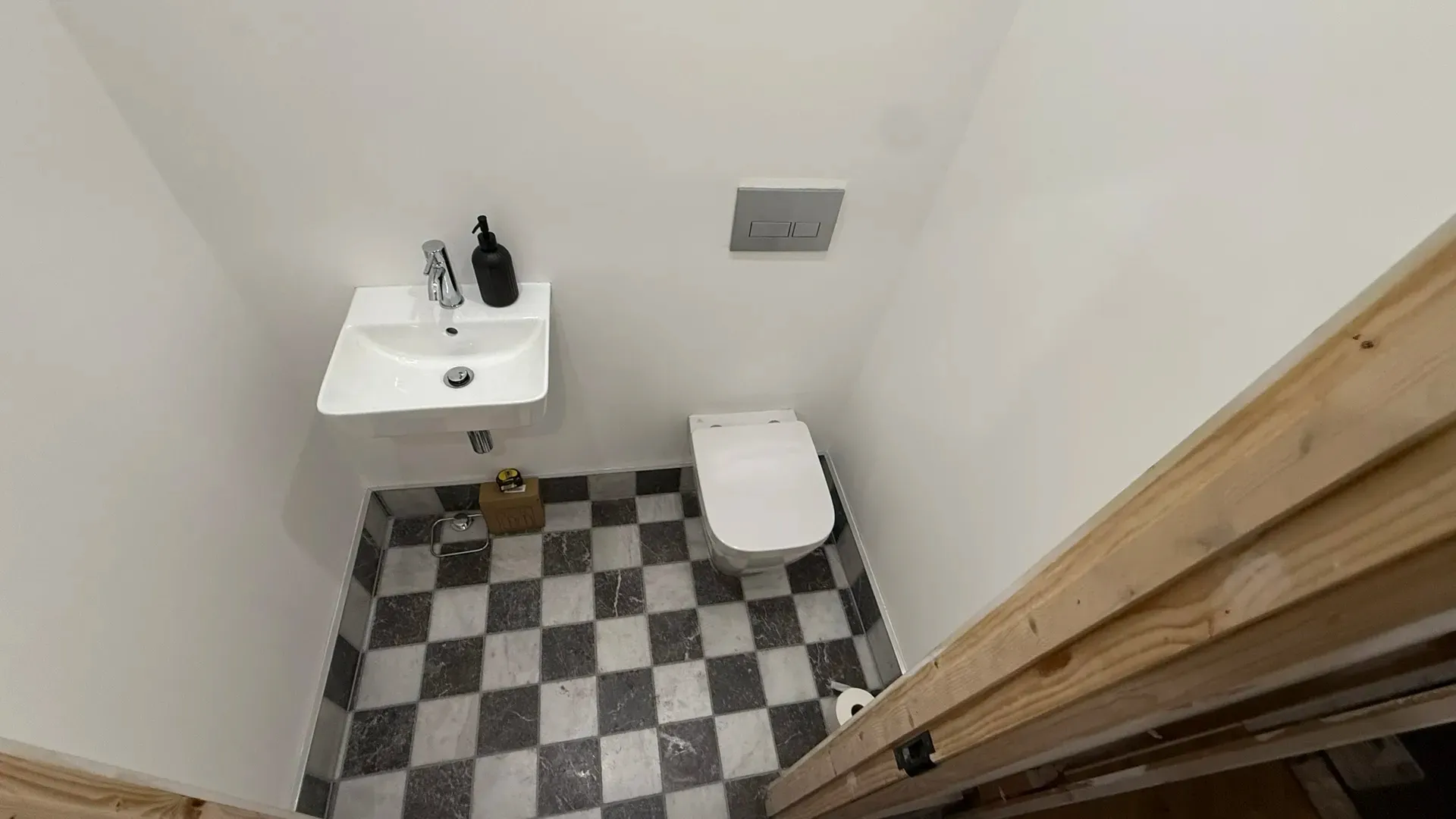 Small cloakroom with a wall-hung basin, concealed cistern and chequerboard floor