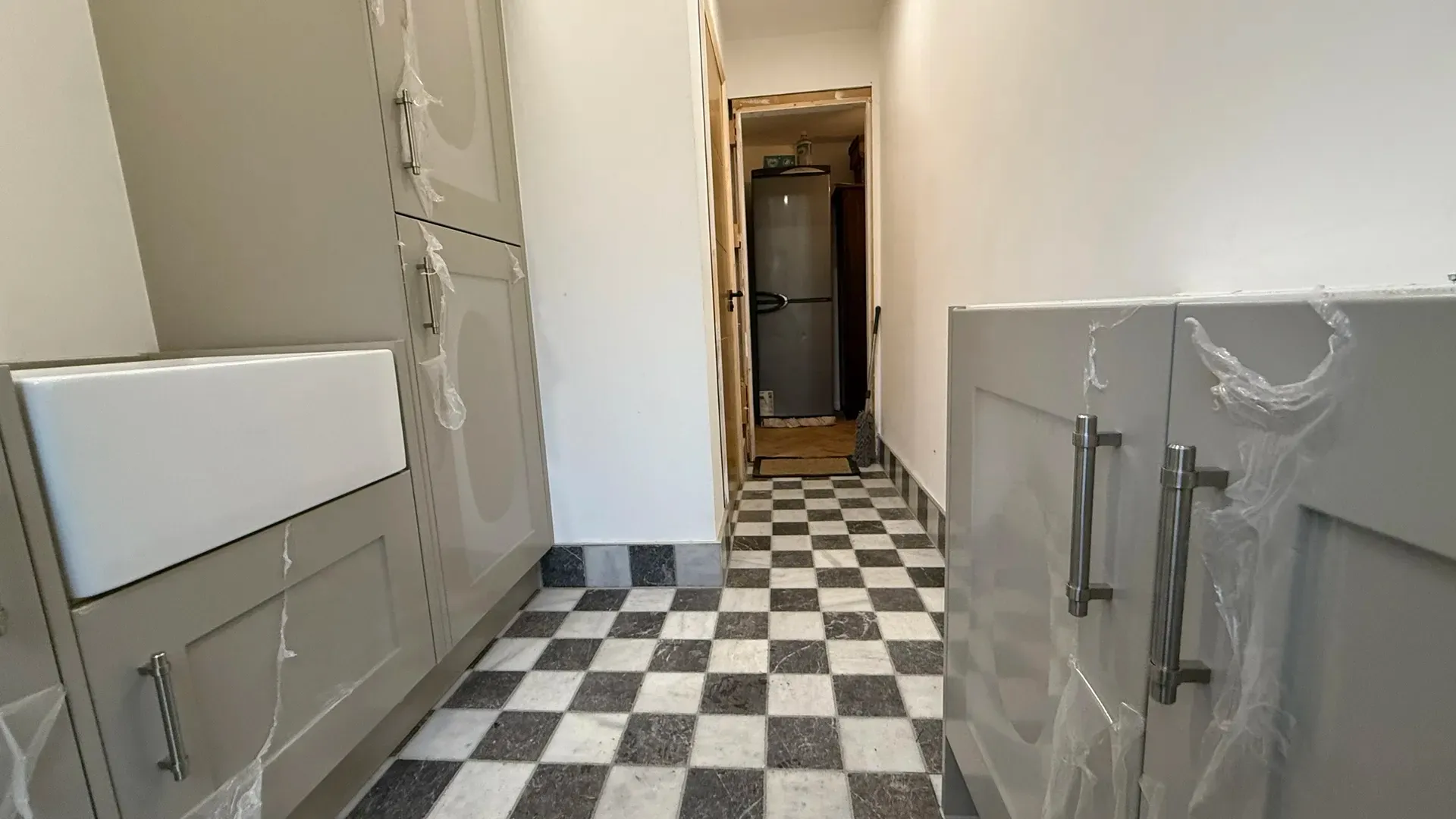 Fitted bathroom furniture beside a chequerboard floor and a glass shower screen