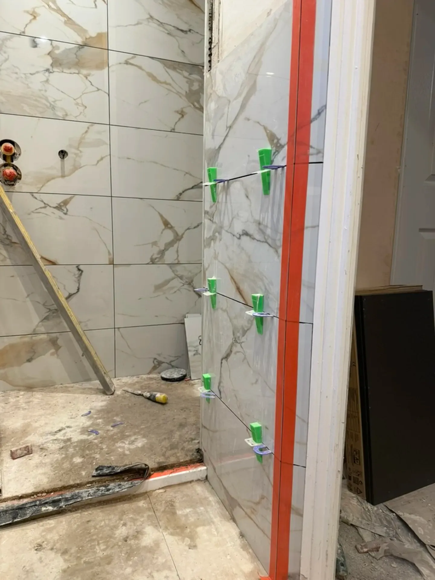 Shower wall tiled with levelling clips still in place during installation