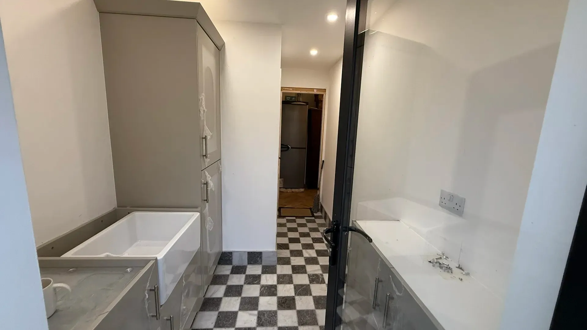 Bathroom with a panelled bath, fitted units and a black and white chequerboard floor