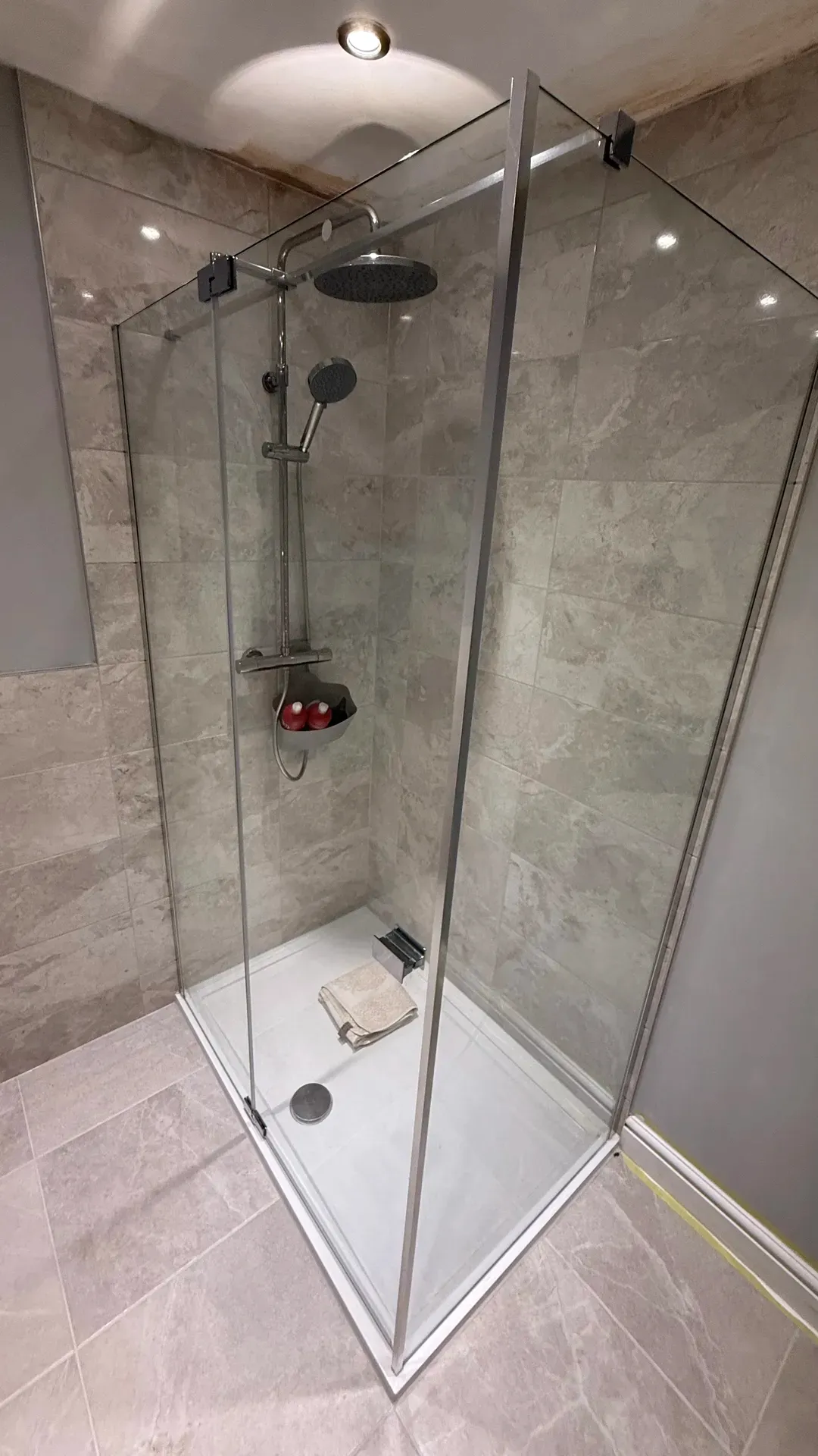 Shower enclosure with a riser rail and grey stone-effect wall tiles