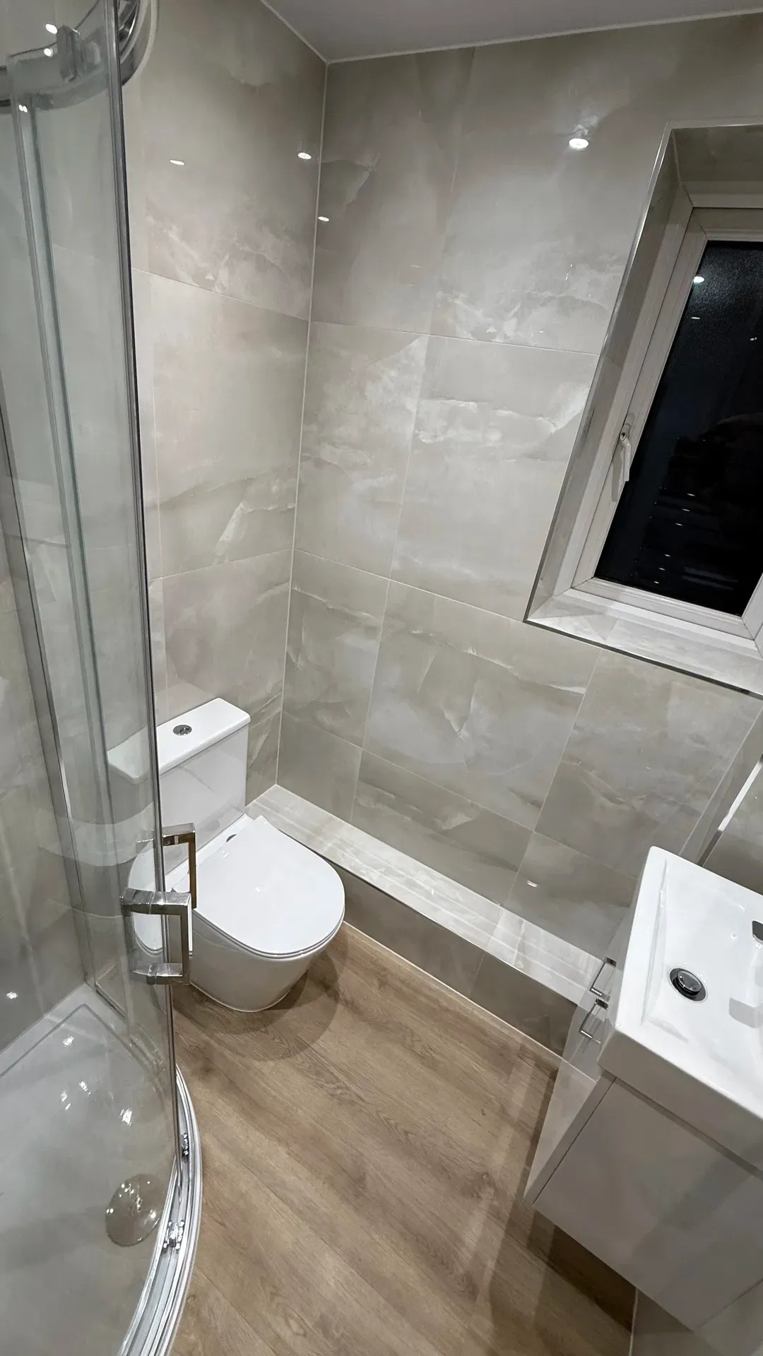 Toilet and shower enclosure under a sloping ceiling with a roof window