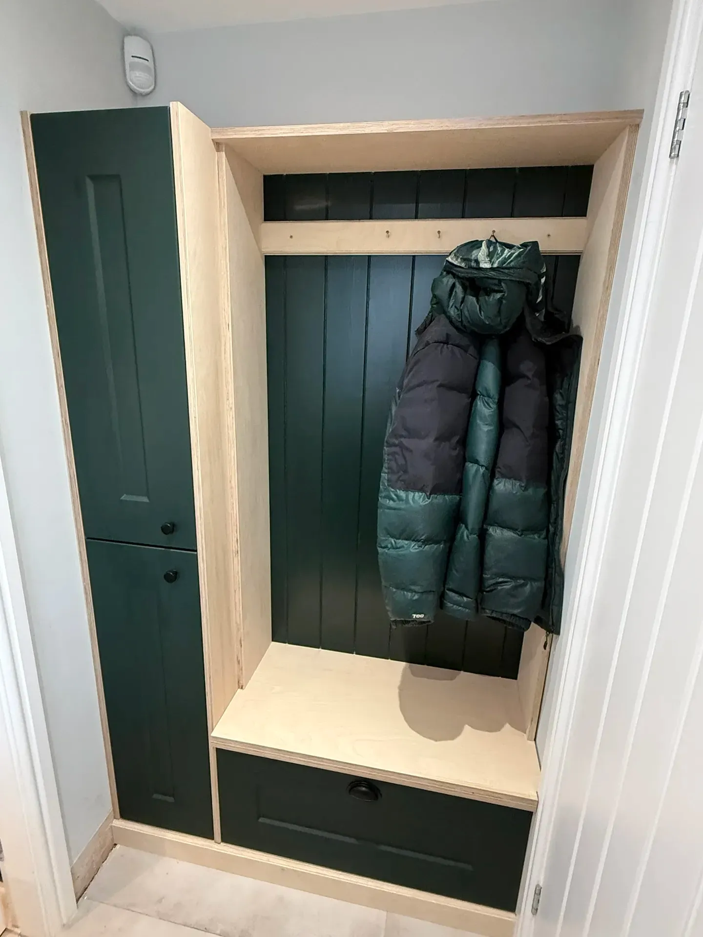 Bespoke boot room with dark green panelling, an oak bench and coat hooks
