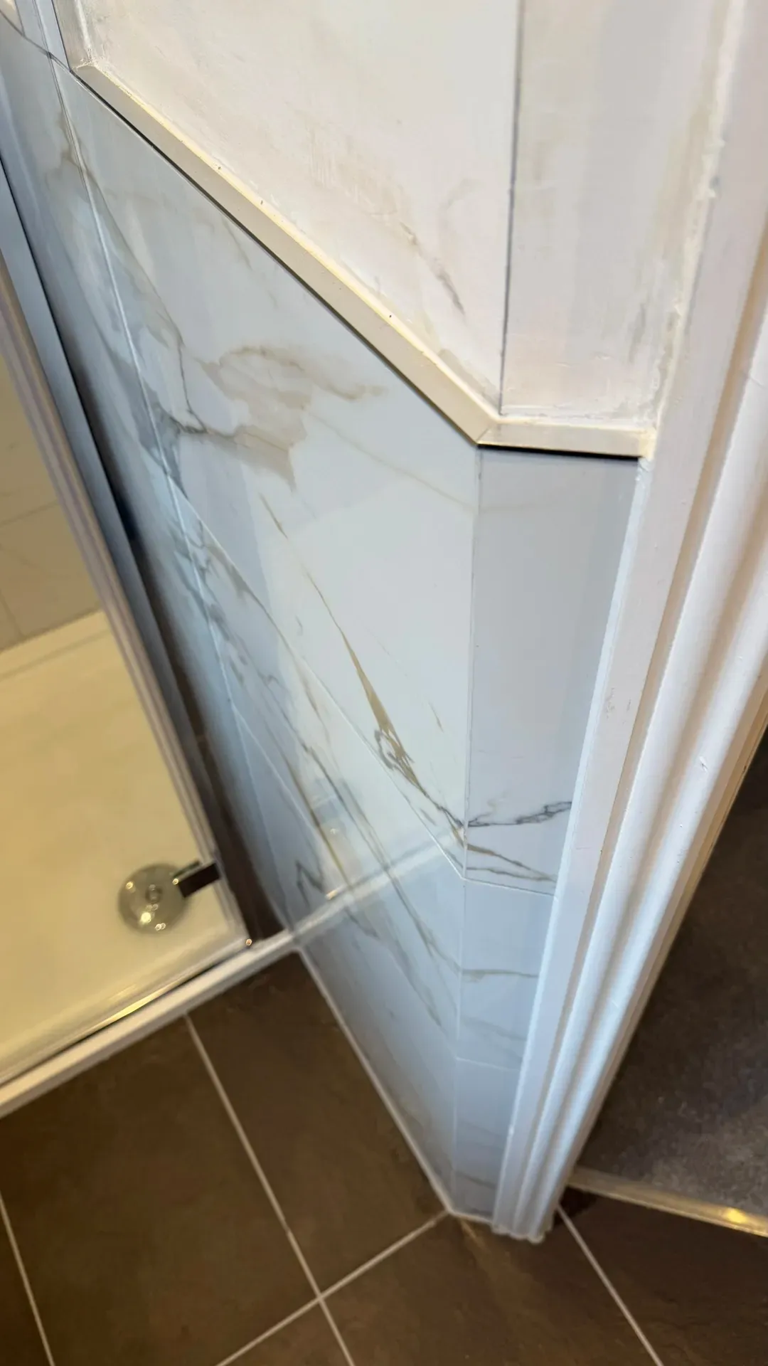 Marble-effect tiling taken up to a sloping ceiling above a bath