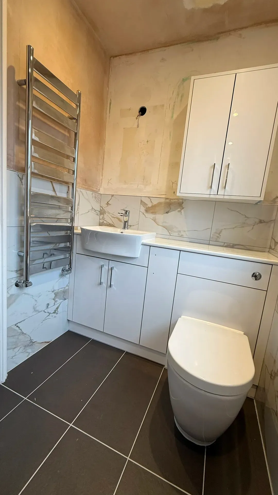 Basin unit, back-to-wall toilet and fitted storage in a marble-effect bathroom
