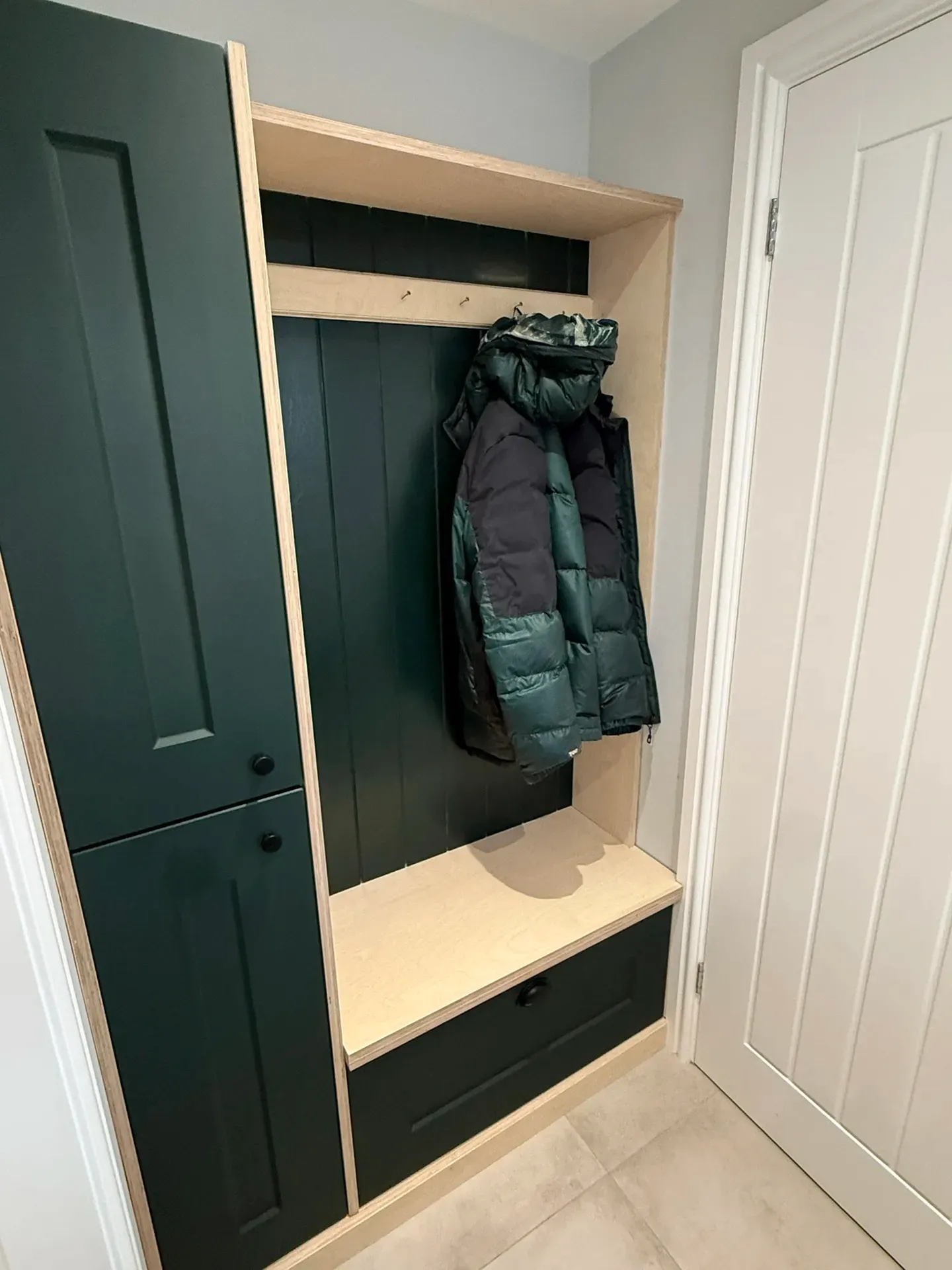 Oak bench seat and drawer in a fitted boot room with green panelling