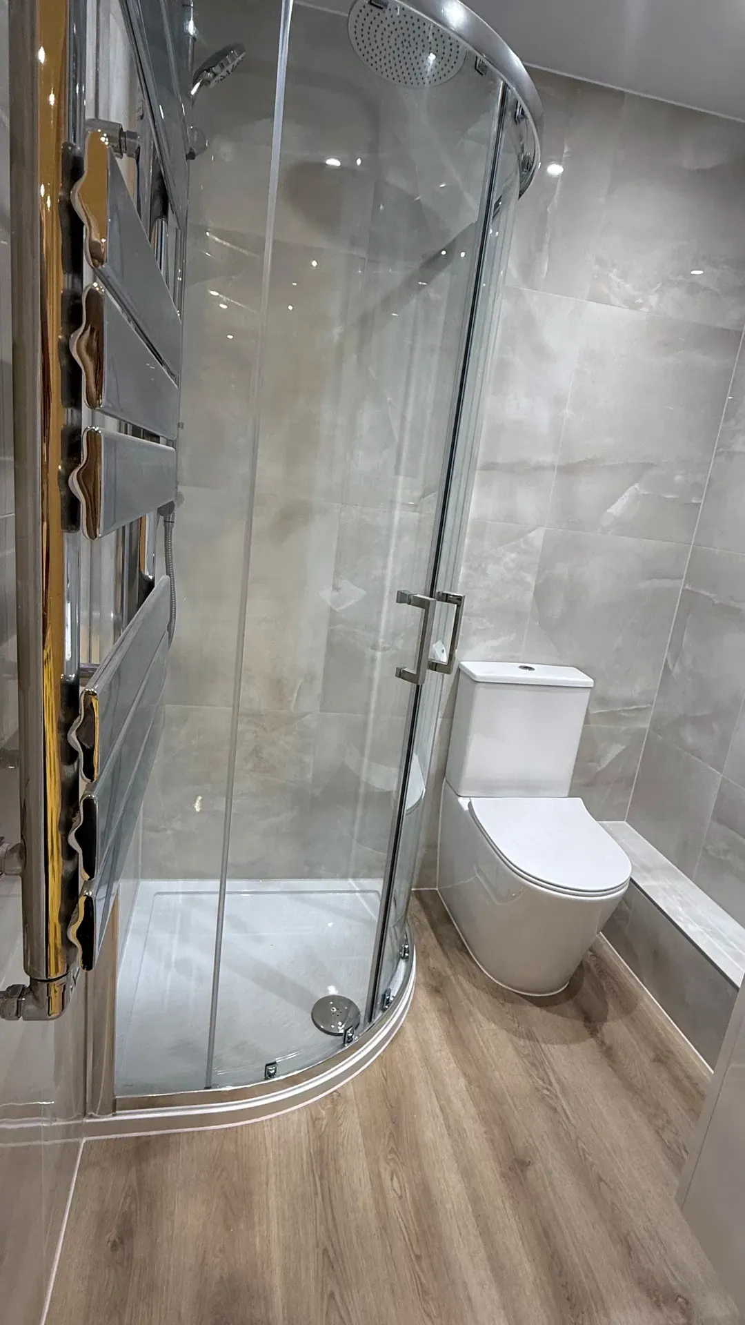 Quadrant shower enclosure and toilet beside a chrome towel radiator