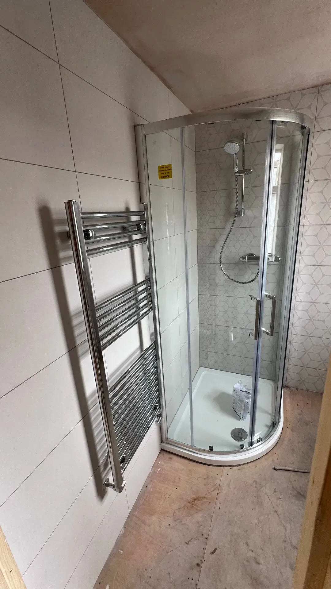 Quadrant shower enclosure beside a chrome ladder towel radiator