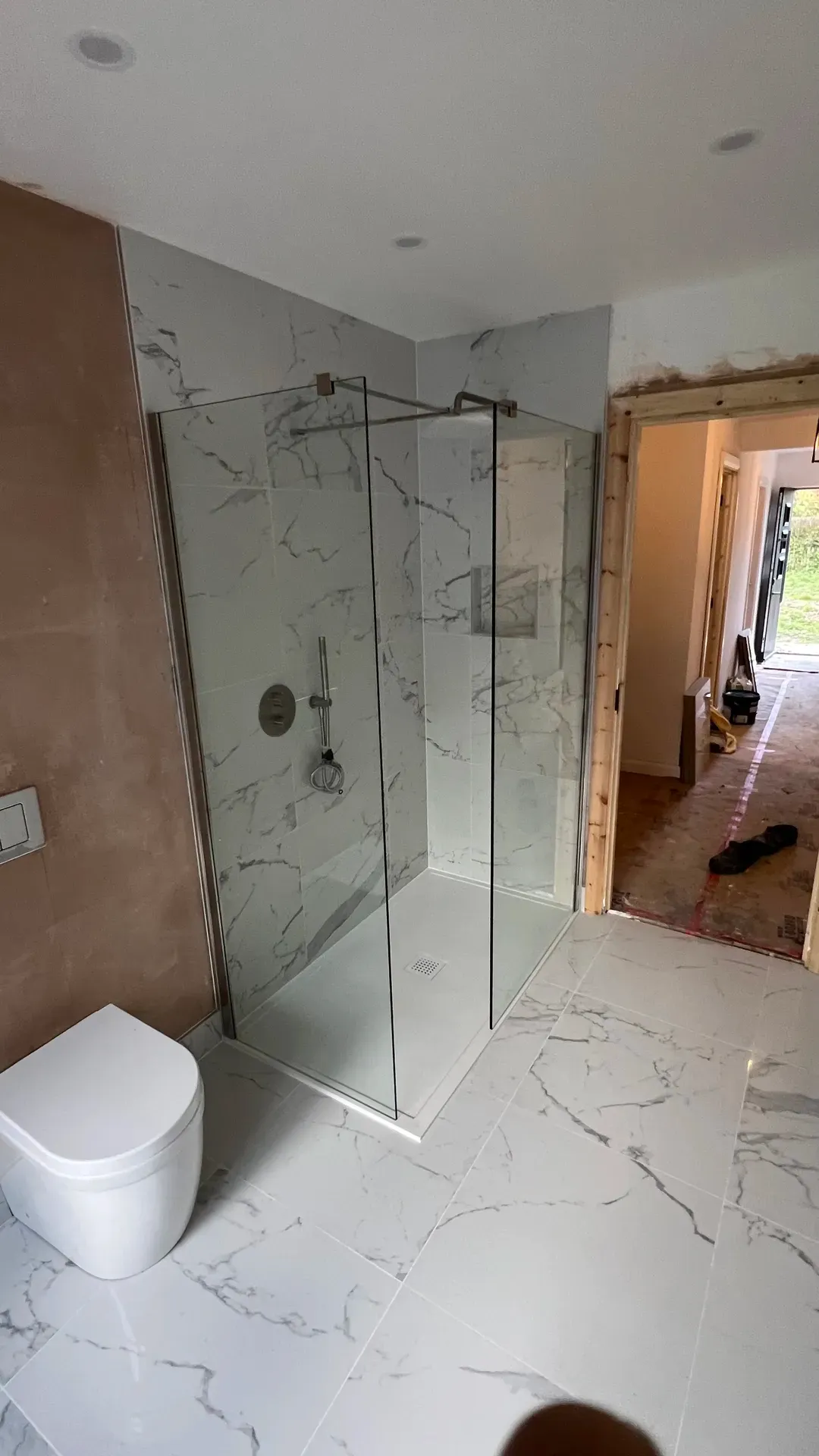 Walk-in shower with a glass screen part-way through a bathroom installation