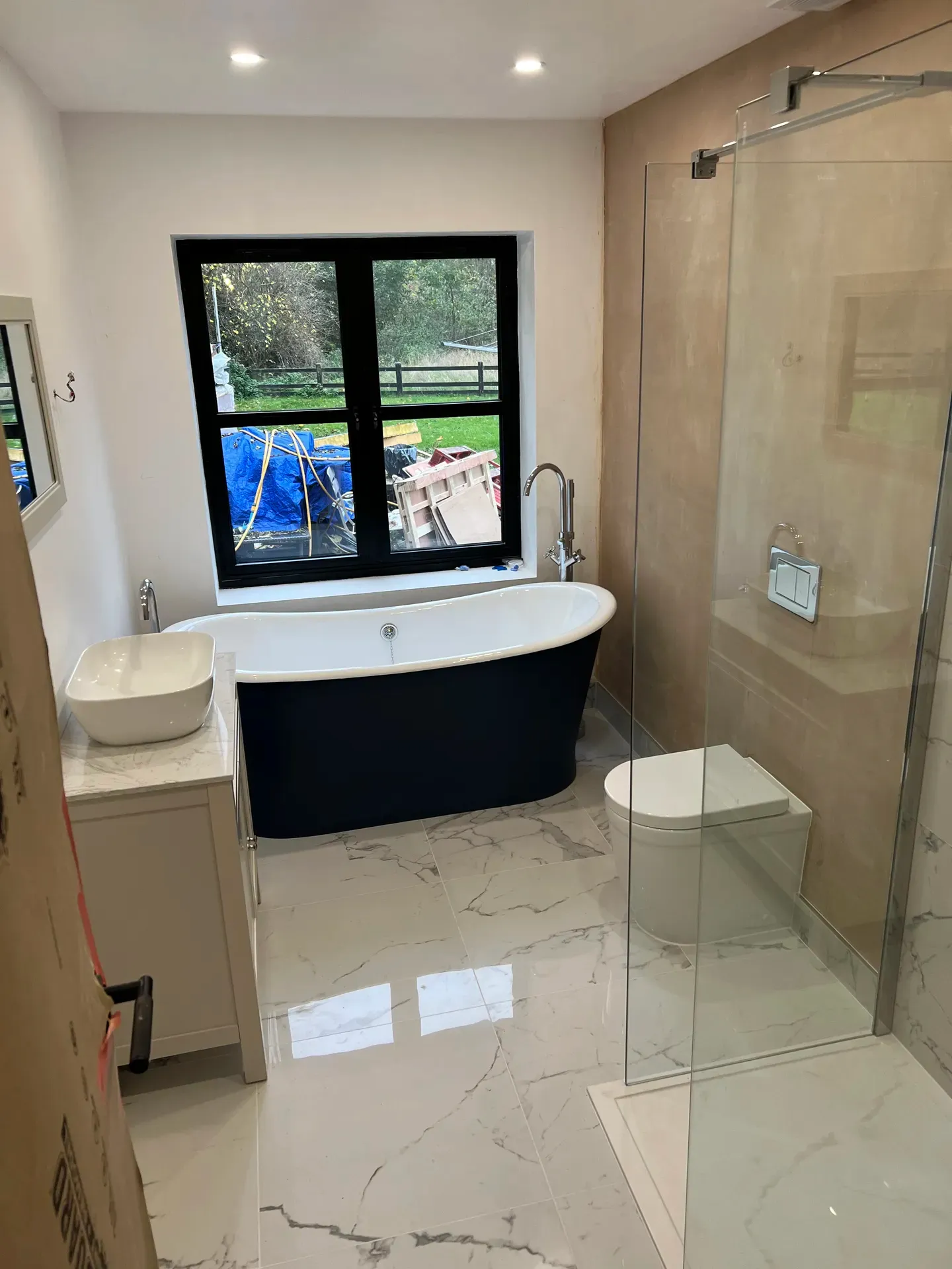 Freestanding bath, walk-in shower and countertop basin in a large tiled bathroom