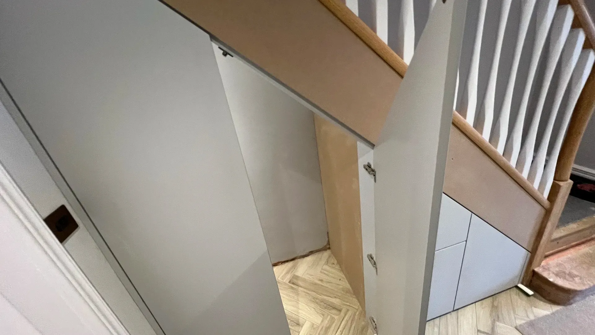 Understairs cupboard doors opened to show the storage formed inside