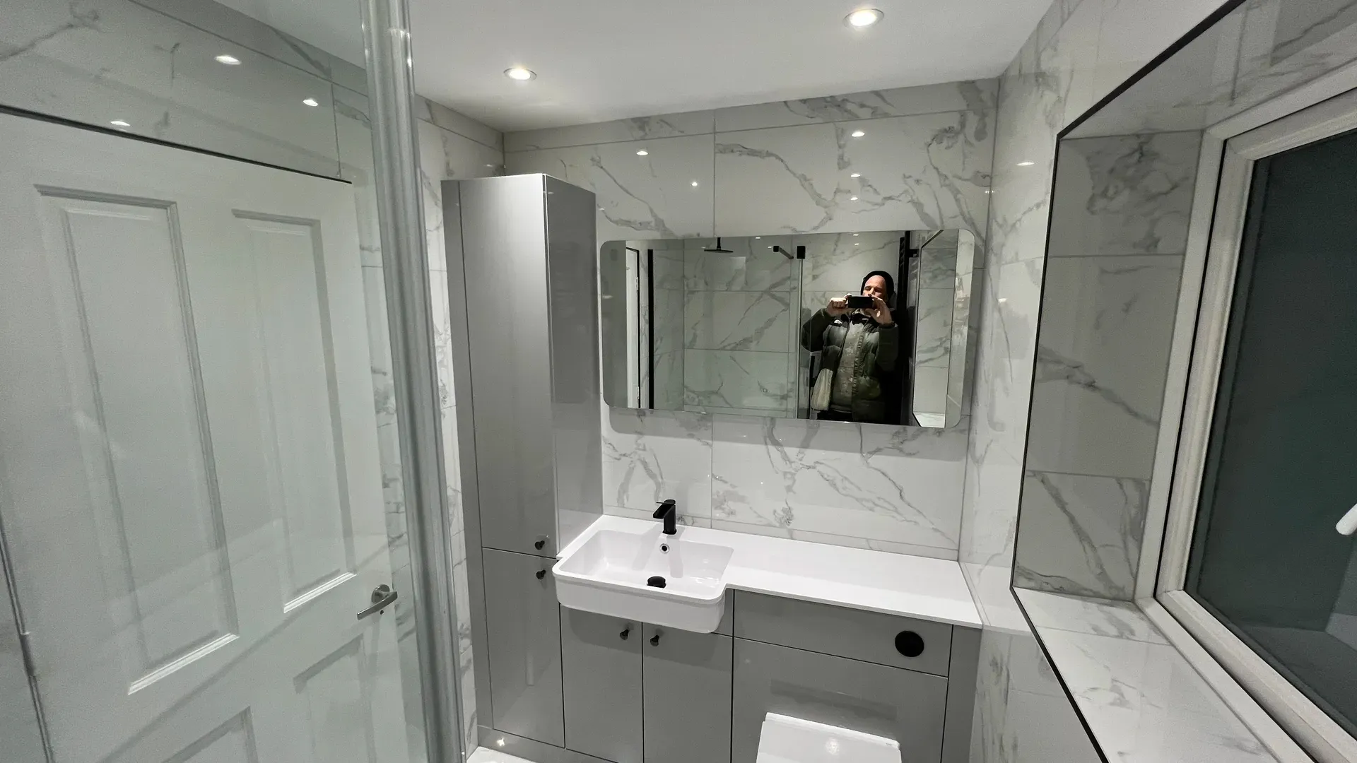 Fitted vanity unit, mirror and shower screen in a marble-effect bathroom