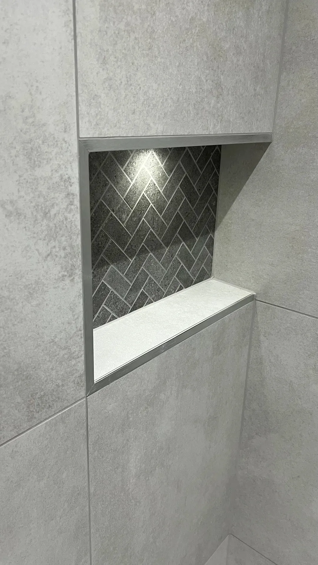 Lit recess with a herringbone-tiled back and a solid shelf