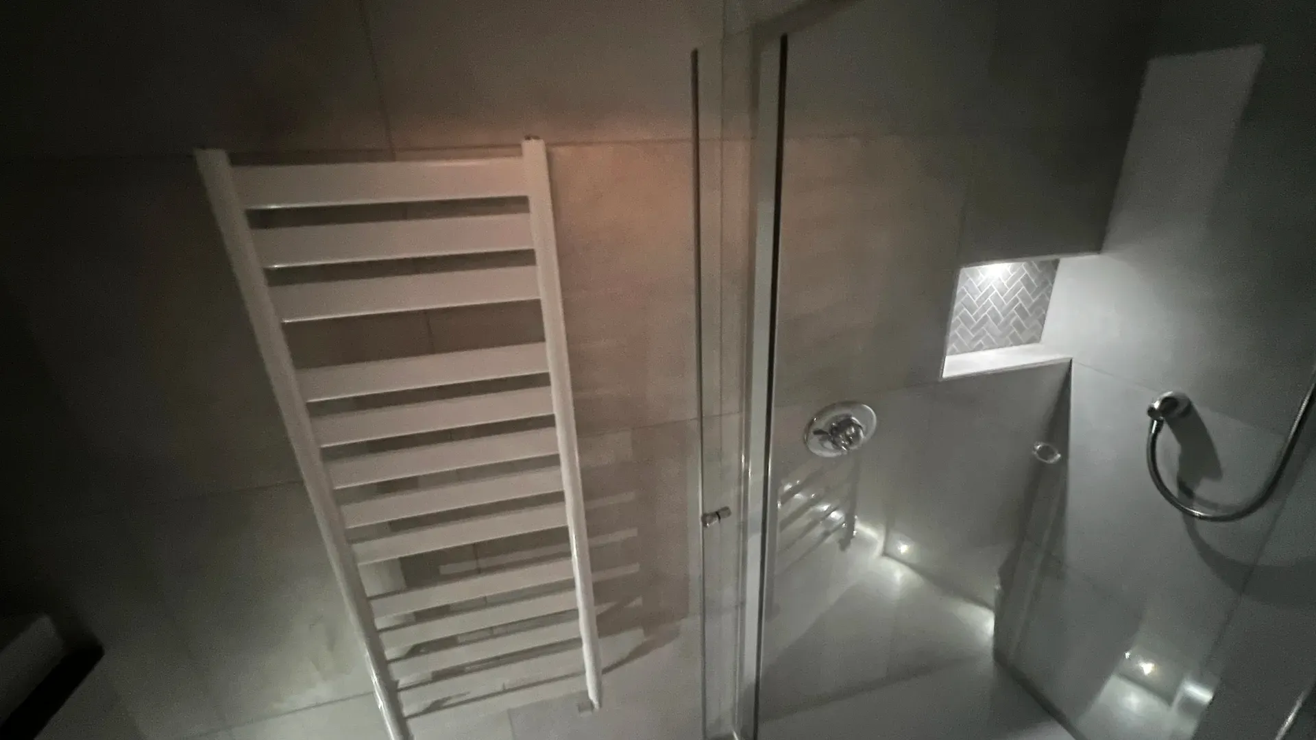 Shower enclosure and towel radiator in a compact tiled shower room