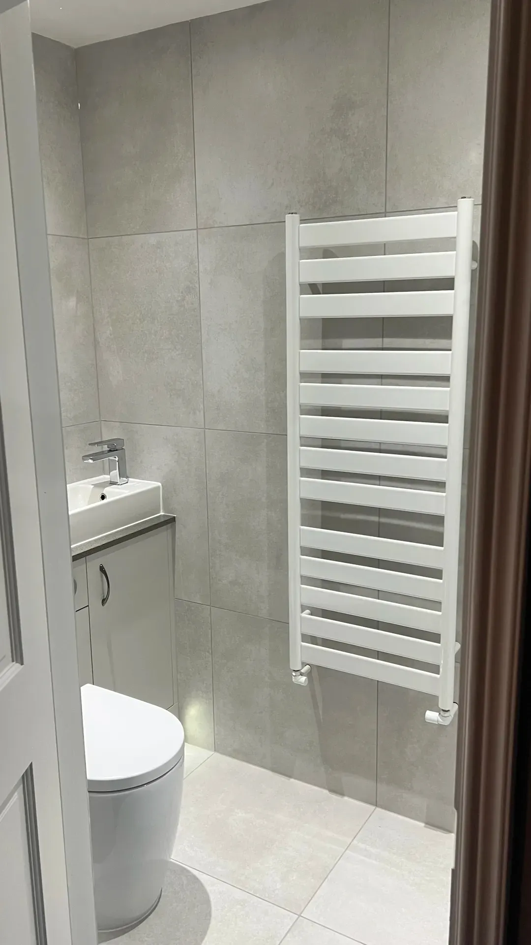 Compact basin unit beside a tall white ladder towel radiator