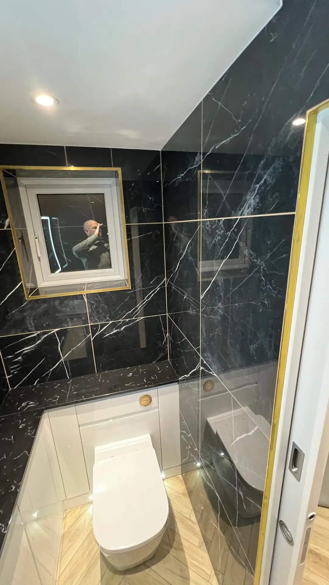 Black marble-effect tiled shower room with a gilt-framed mirror