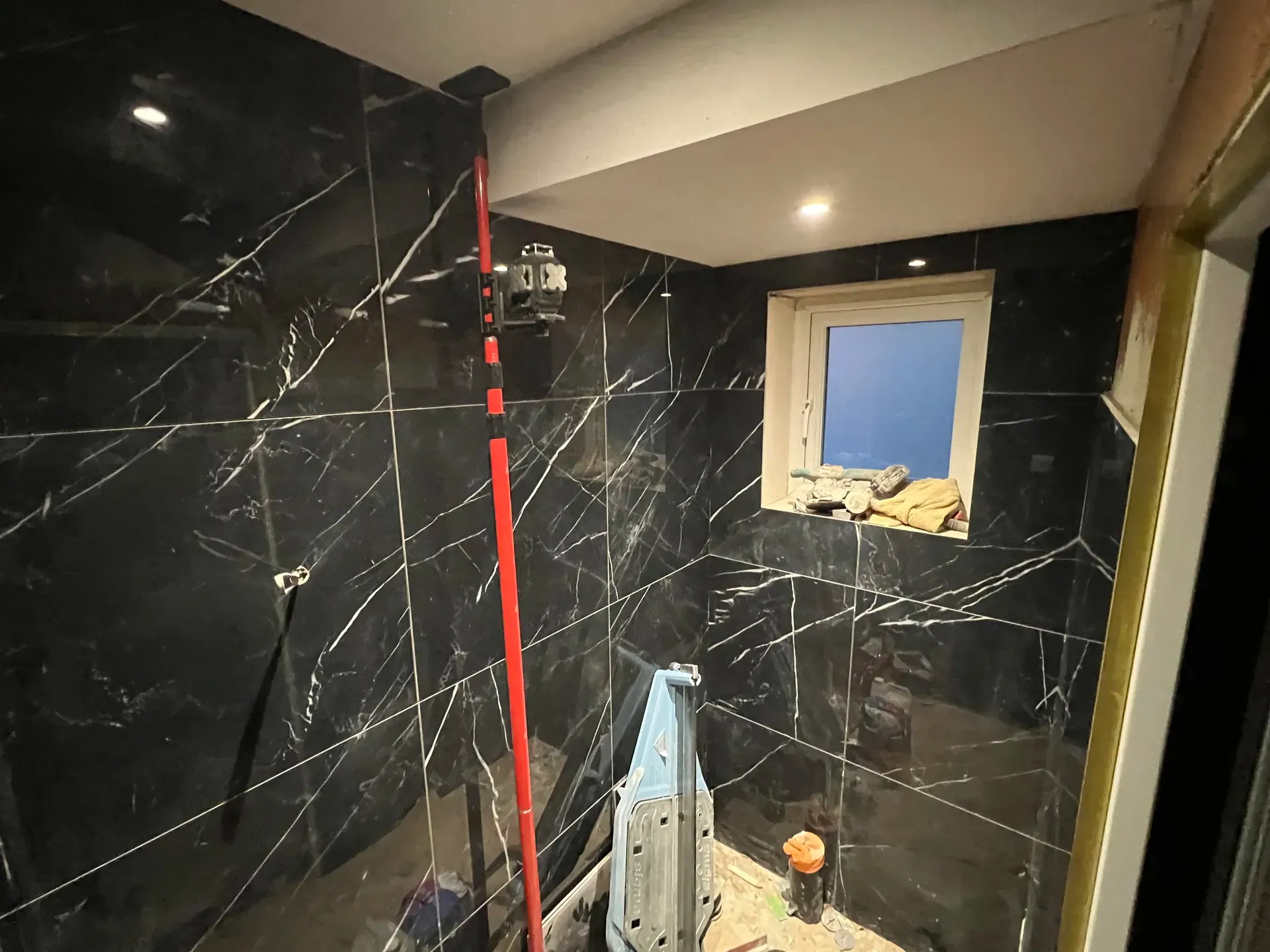 Black marble-effect wall tiling being set out during installation