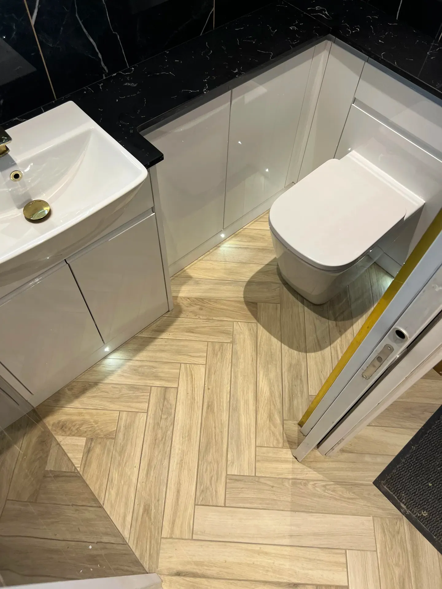 Vanity basin and wall-hung toilet above a herringbone wood-effect floor