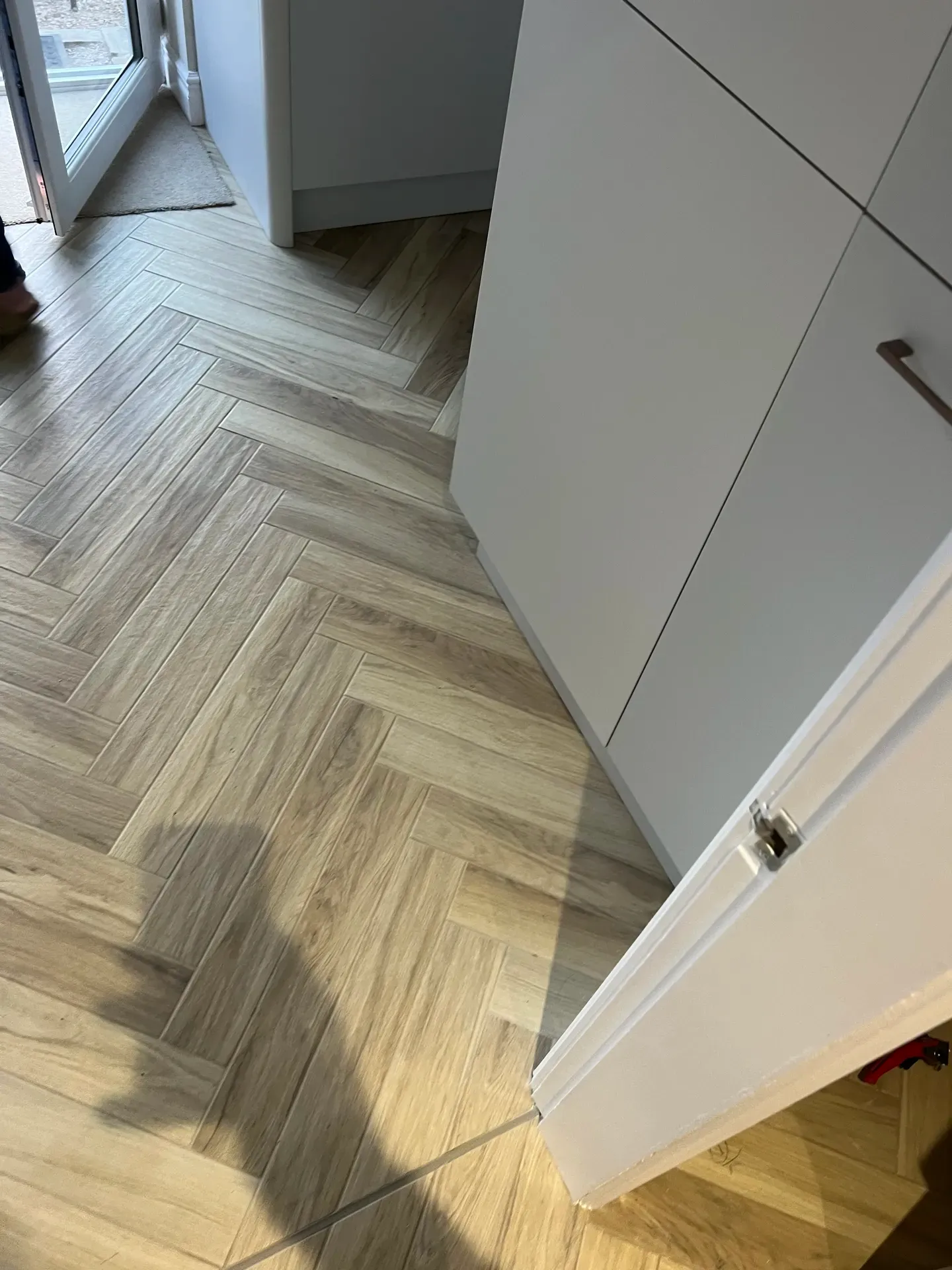 Herringbone wood-effect flooring laid up to fitted kitchen units