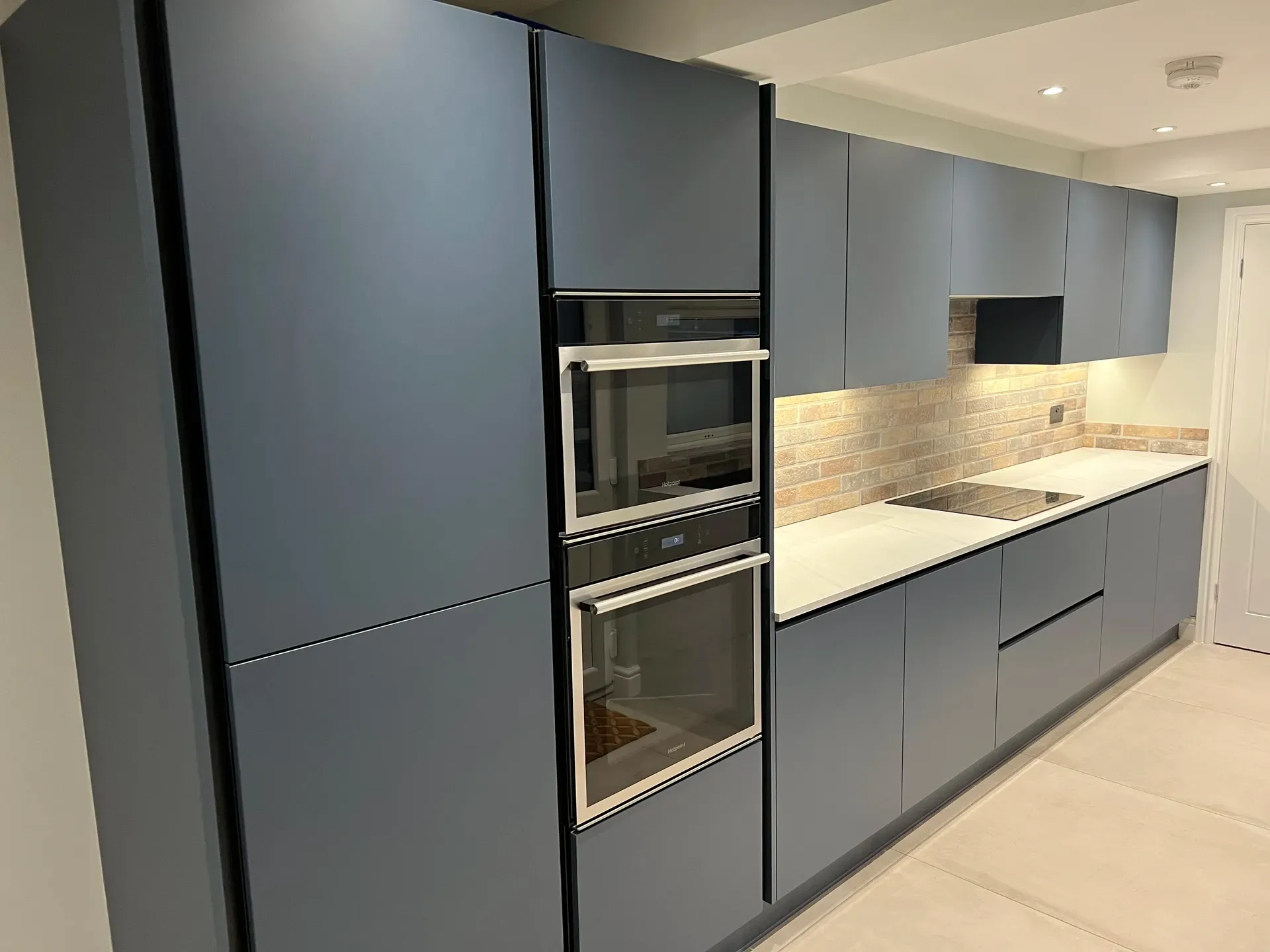 Handleless dark blue cabinet doors and a built-in oven housing